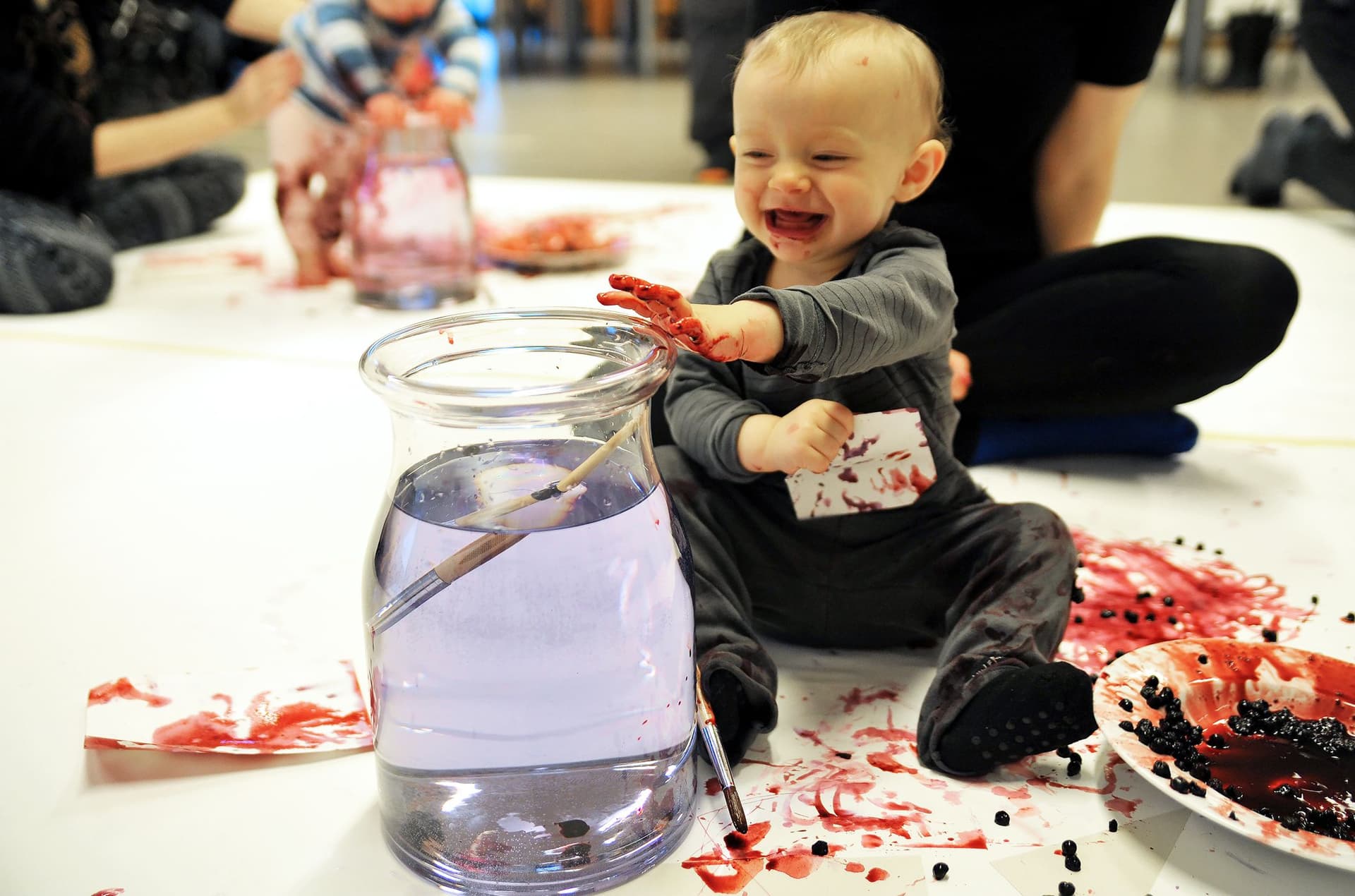 Skrattande bebis kladdig av blåbär