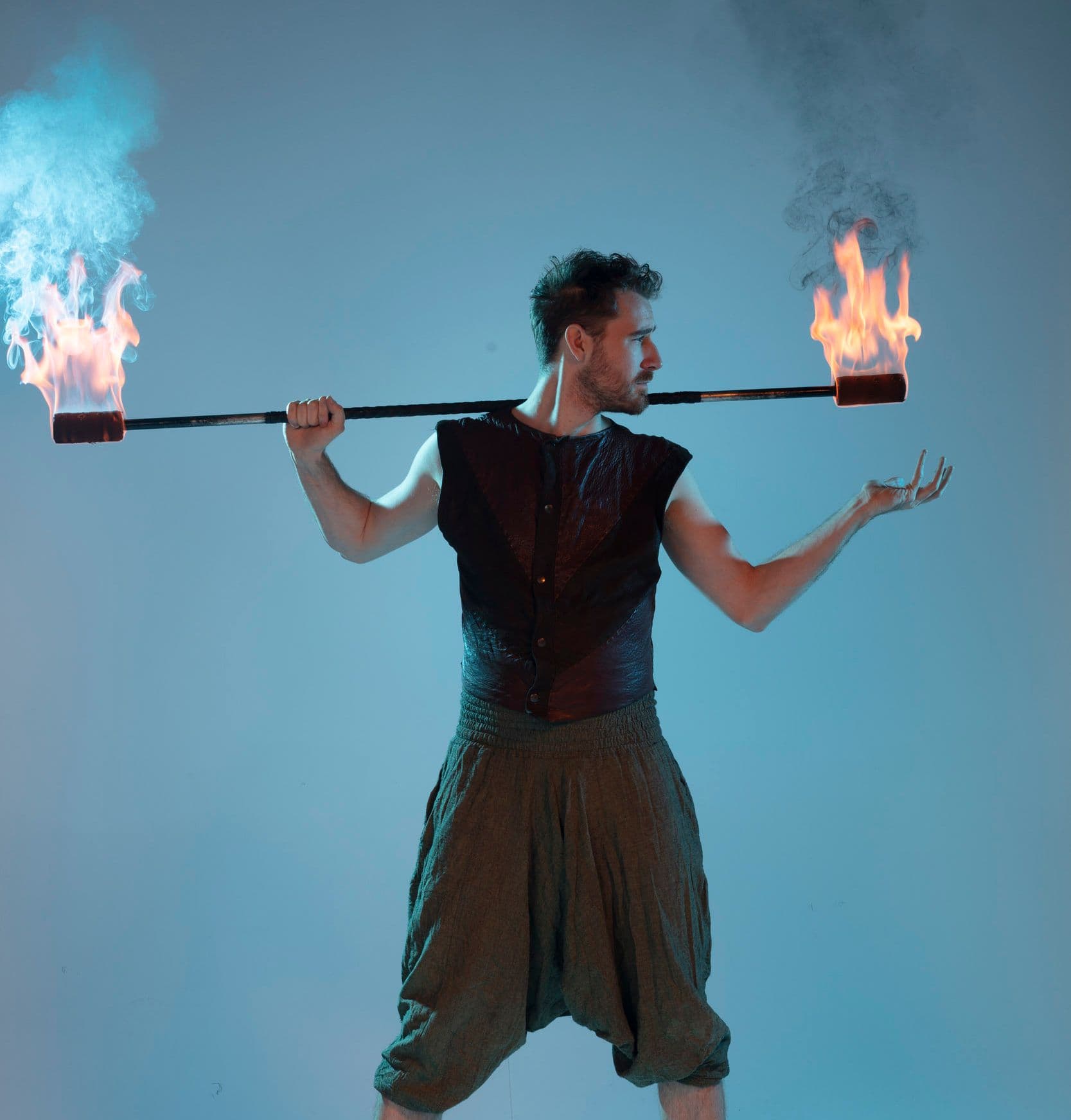 Person med blå bakgrund med eldstav i händerna