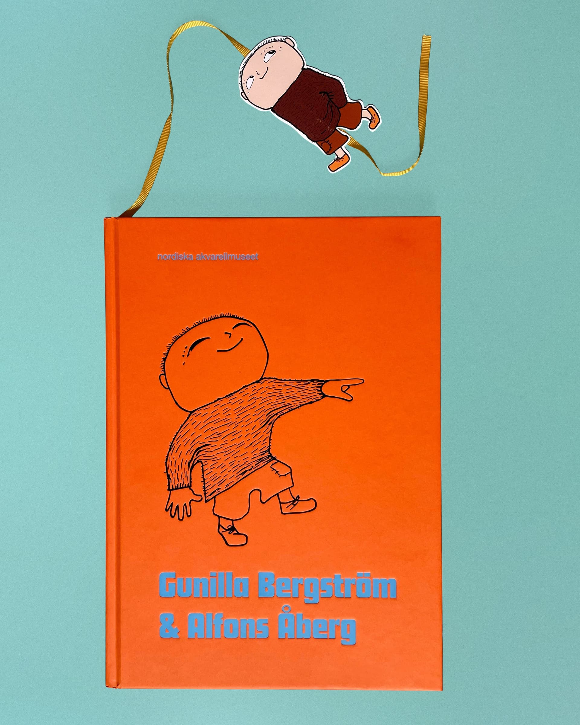 Bild på orange bok med titeln Gunilla Bergström och Alfons Åberg mot turkos bakgrund
