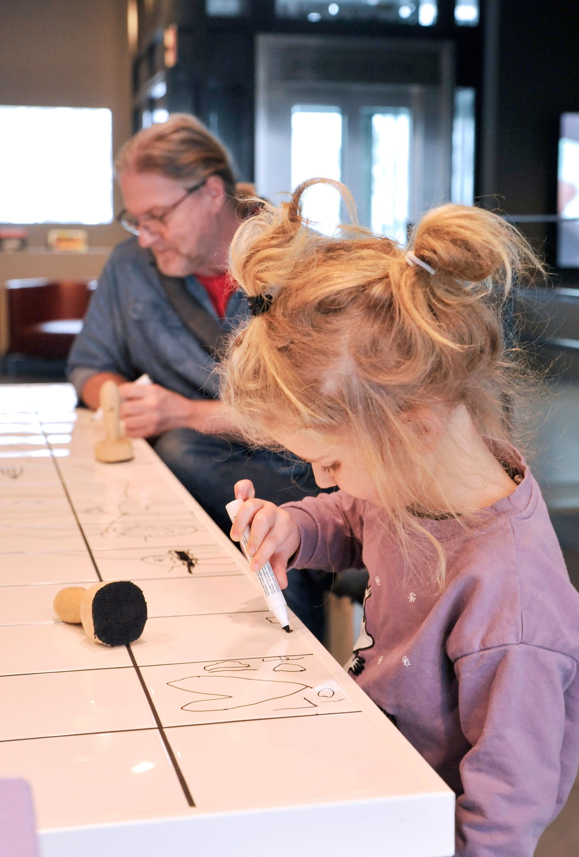 Barn som ritar på ett bord med kakelplattor