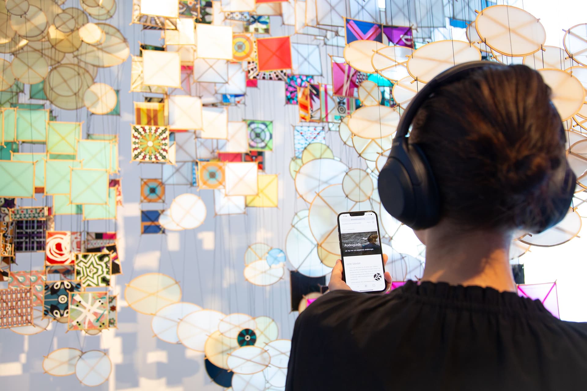 Person med hörlurar tittar på verk av Jacob Hashimoto