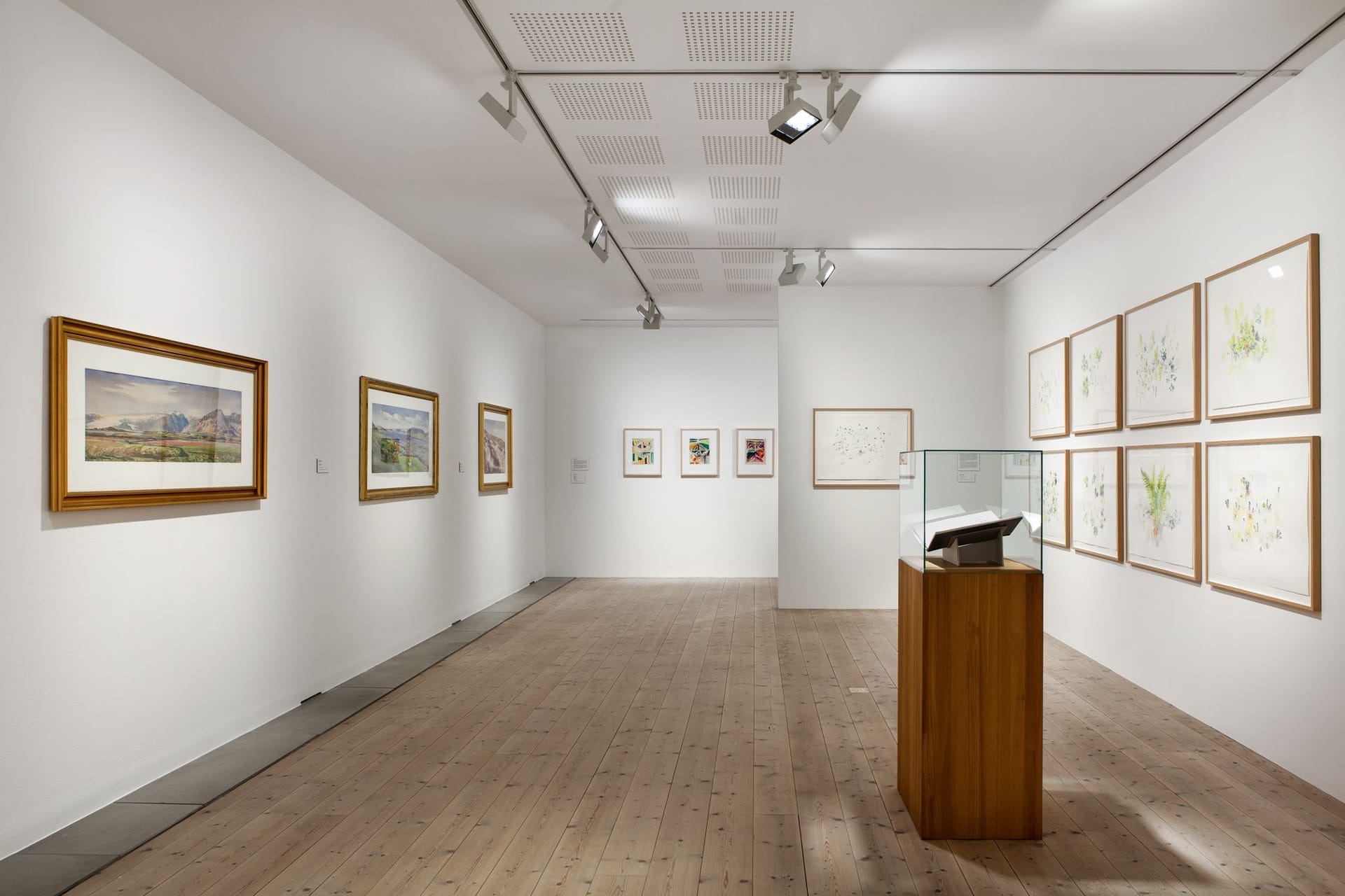 Exhibition room with paintings and a displayed book