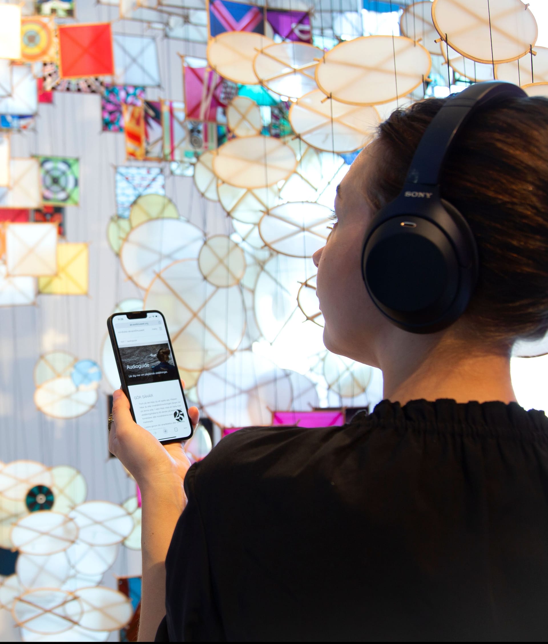 Person with headphones looking at artwork by Jacob Hashimoto