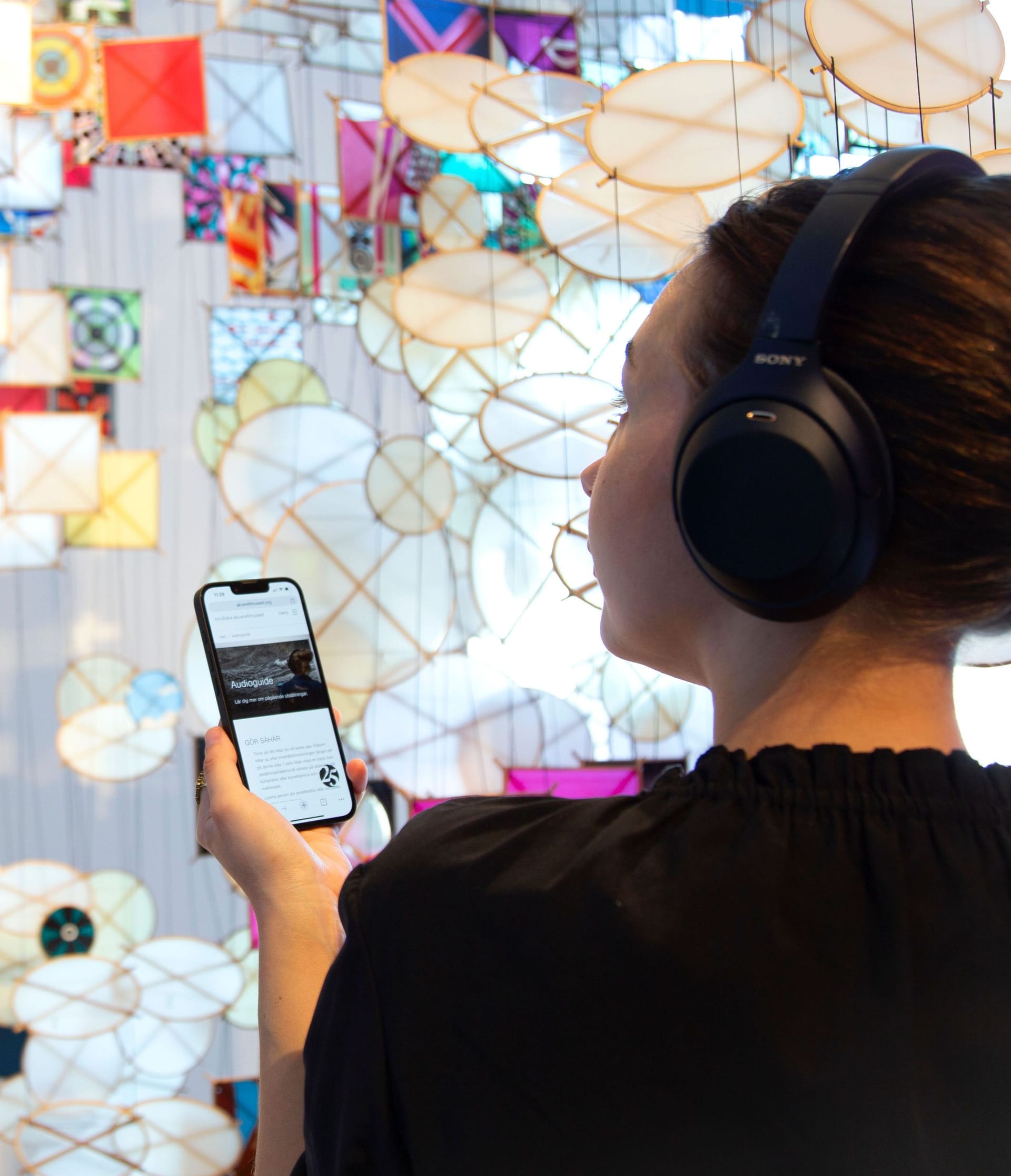Visitor in front of art work with headphones on