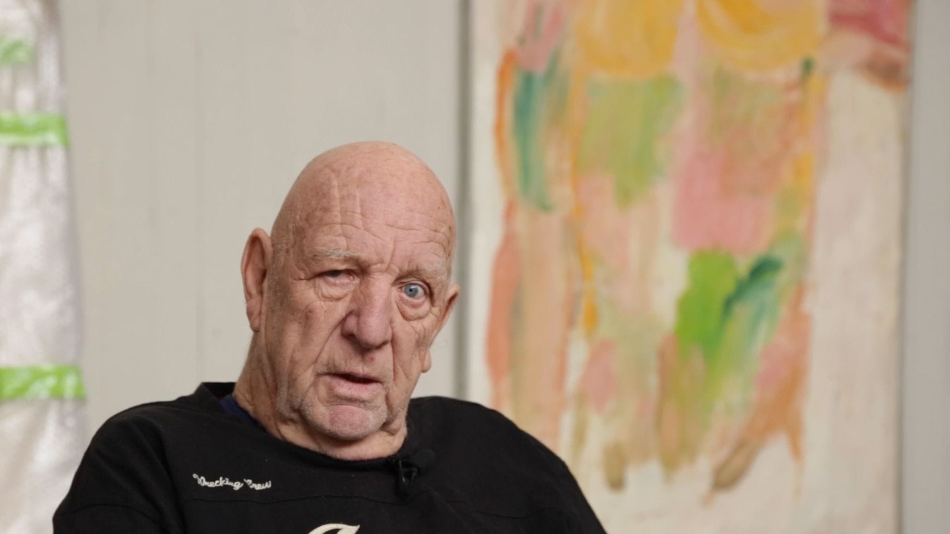 Claes Hake looks into the camera, with painting behind him