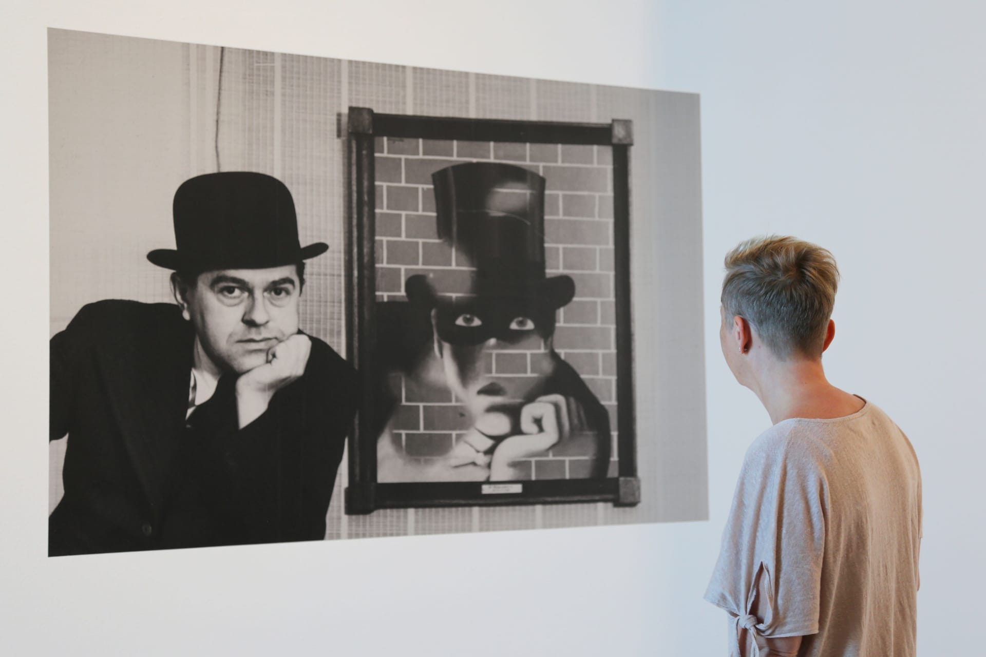 Foto på Magritte bredvid ’The Barbarian’, 1938, samt rygg på besökare