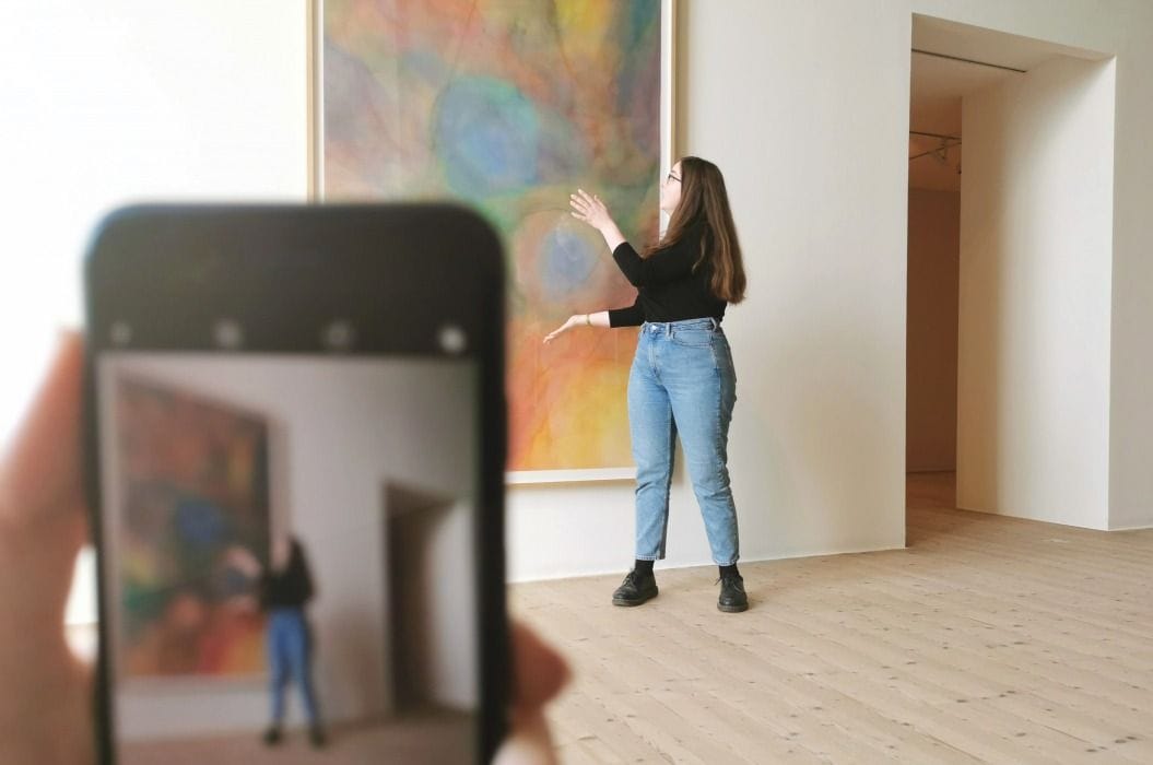 Guide in front of an art work, with cellphone in the foreground