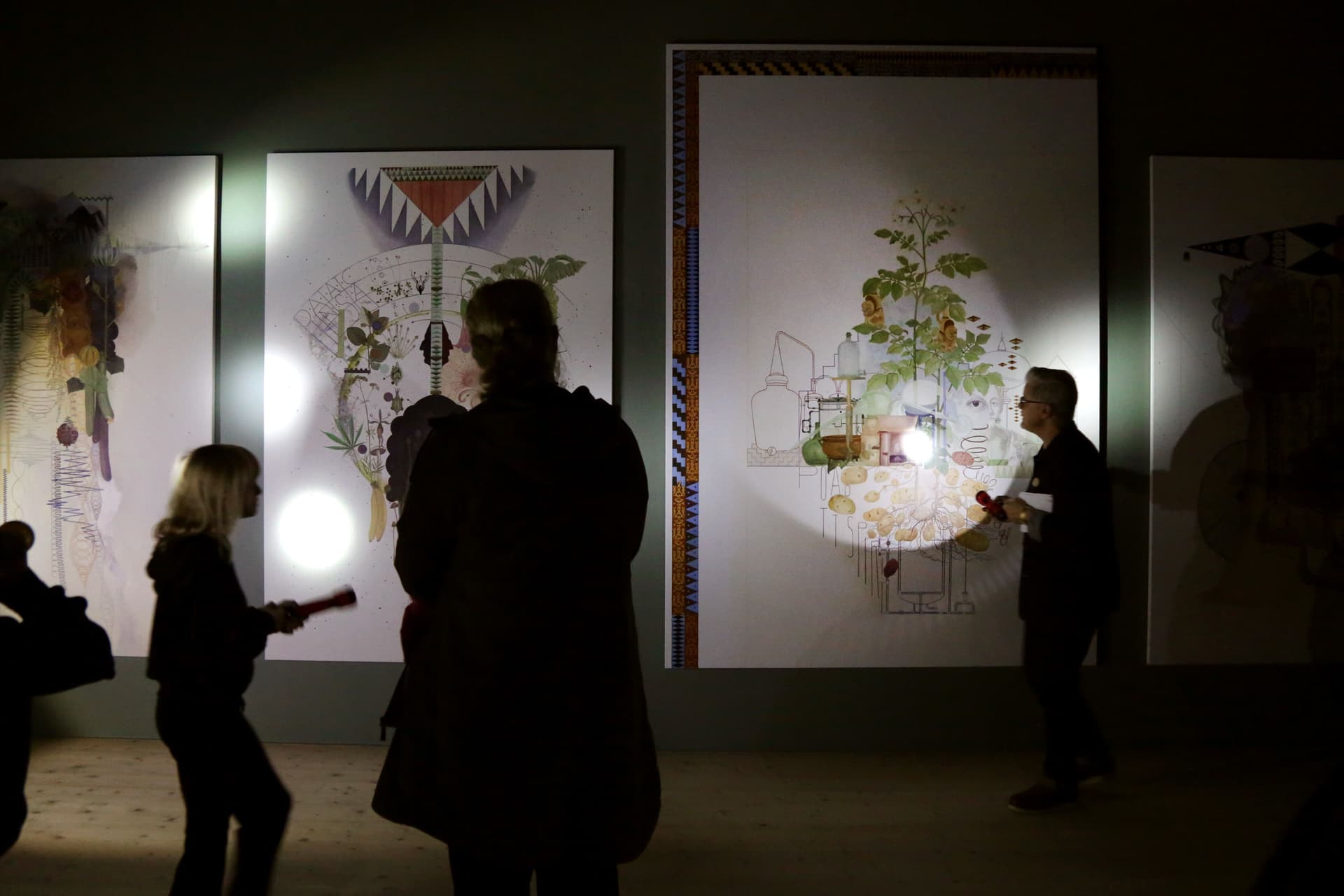 Mörk bild med siluetter och tavlor i ficklampssken