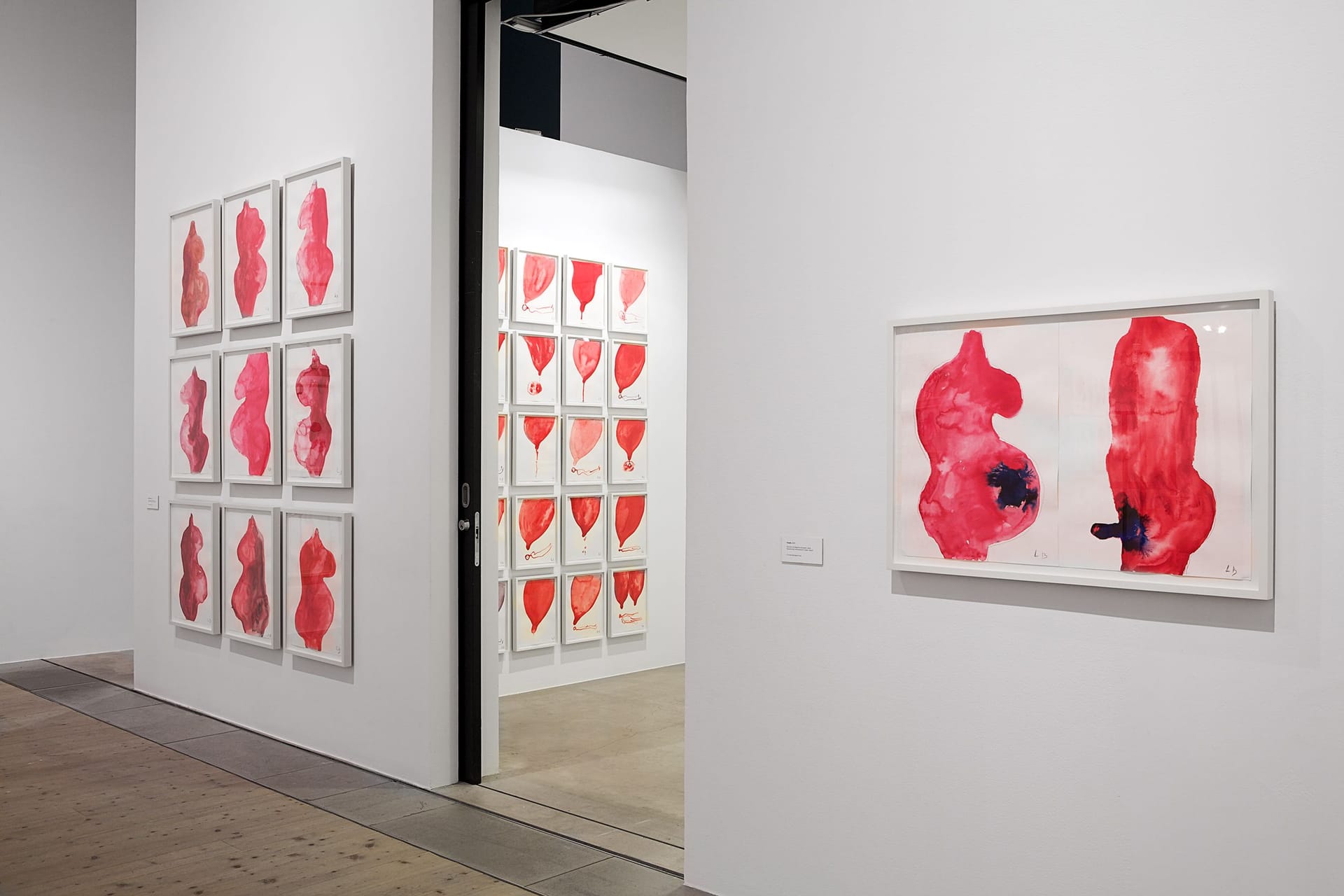 Utställningsrum med röda gouachemålningar av Louise Bourgeois