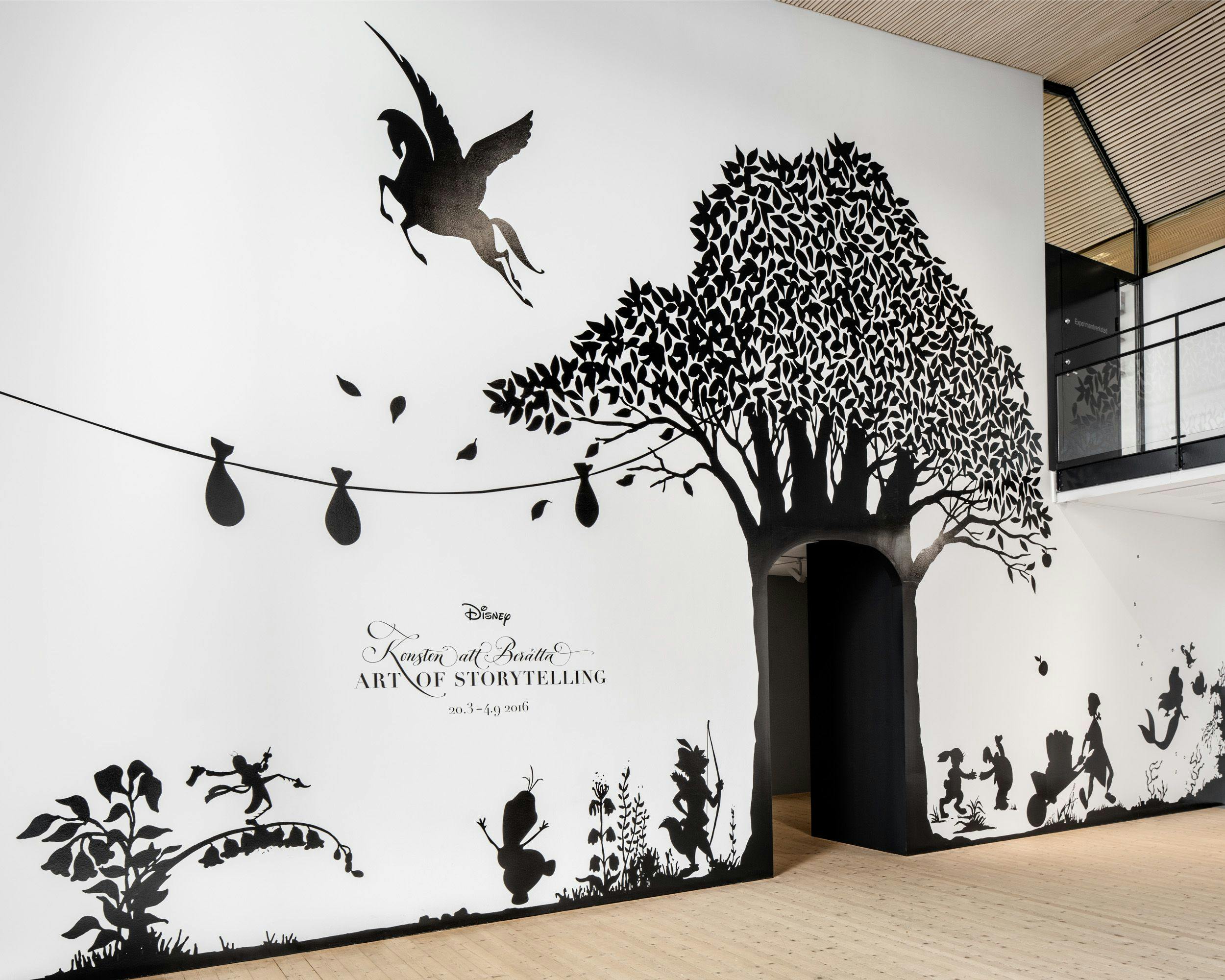 The entrance to the exhibition, with a large mural of silhouettes of famous Disney characters