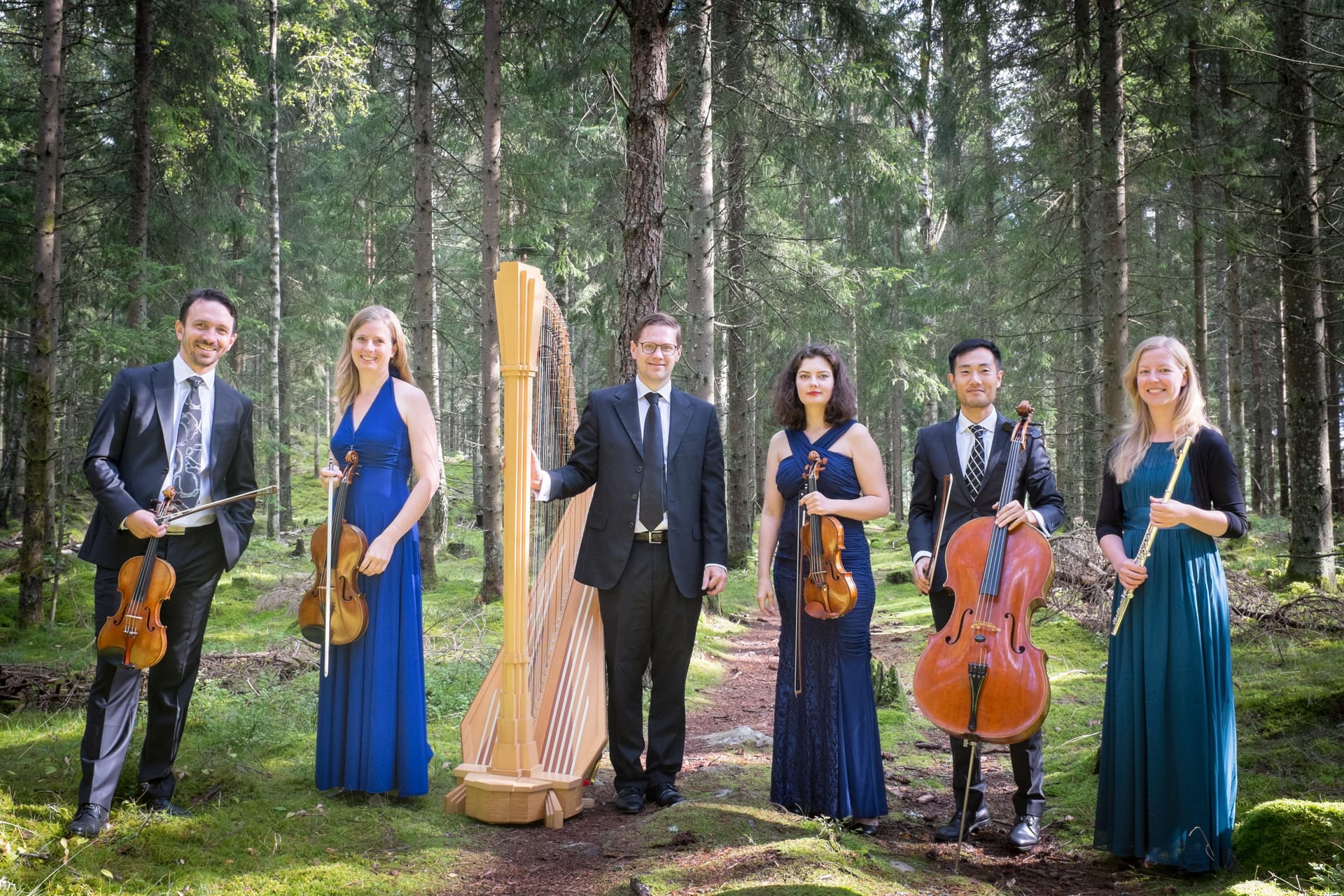 Picture of six musicians from Ensemble Cáplet in the forest