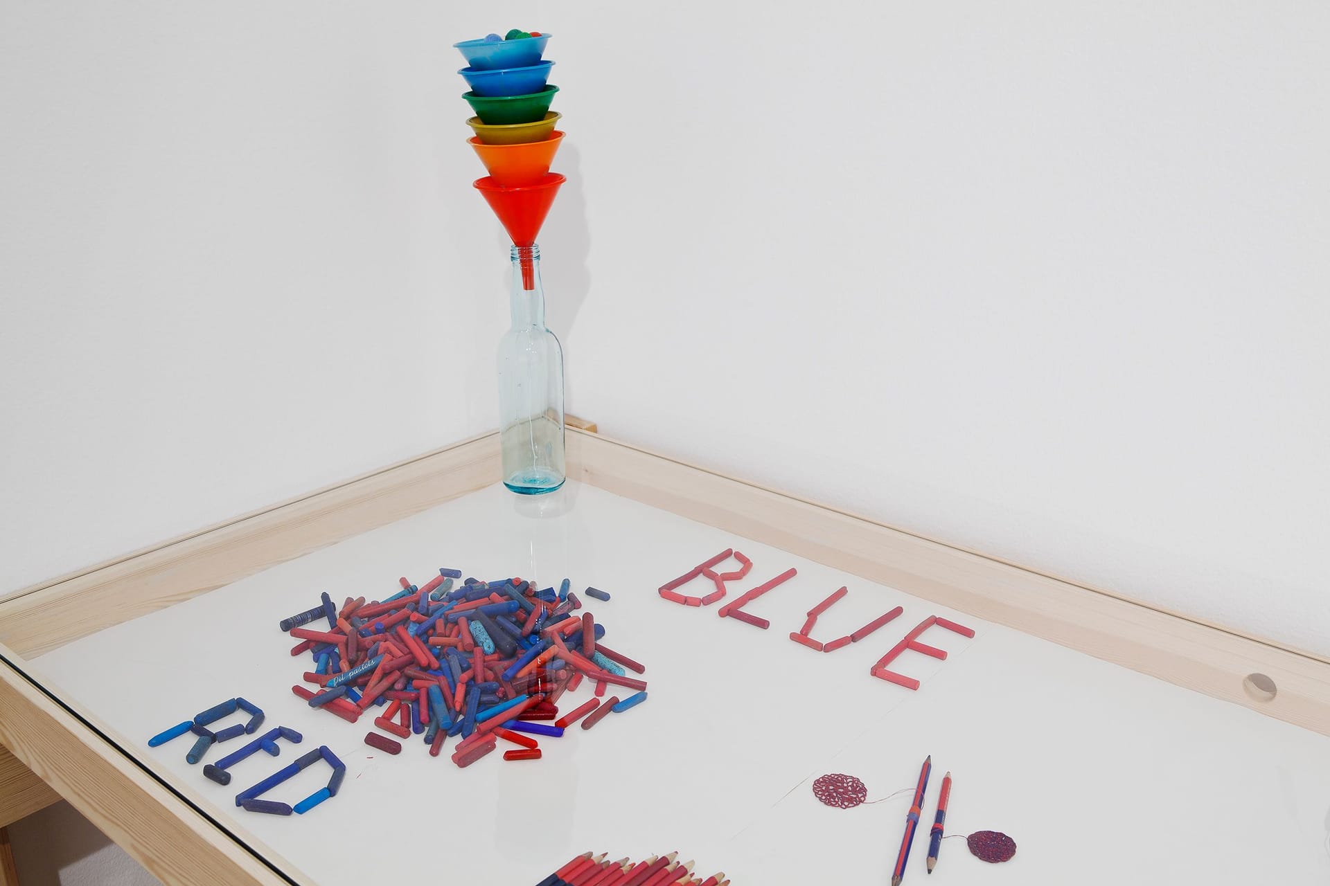 A work by Anu Tuominen in a display case. The word "Blue" is written in red crayons.