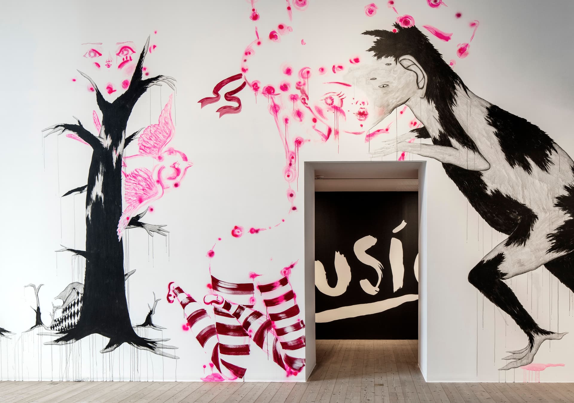 Mural by Katja Tukiainen and Sigga Björg Sigurðardóttir. White wall with black and pink figures.