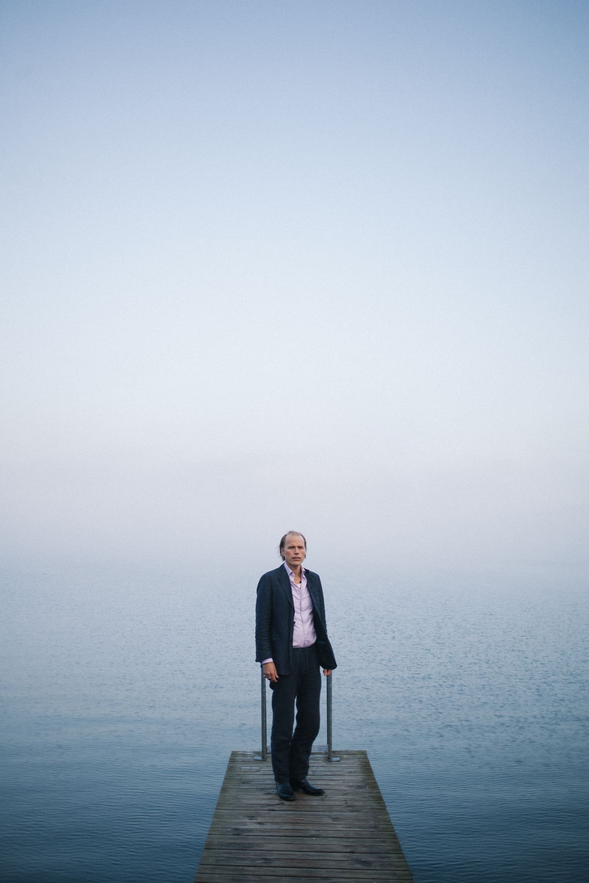 Foto på Christian Kjellvander på brygga mot blå disig havs-bakgrund