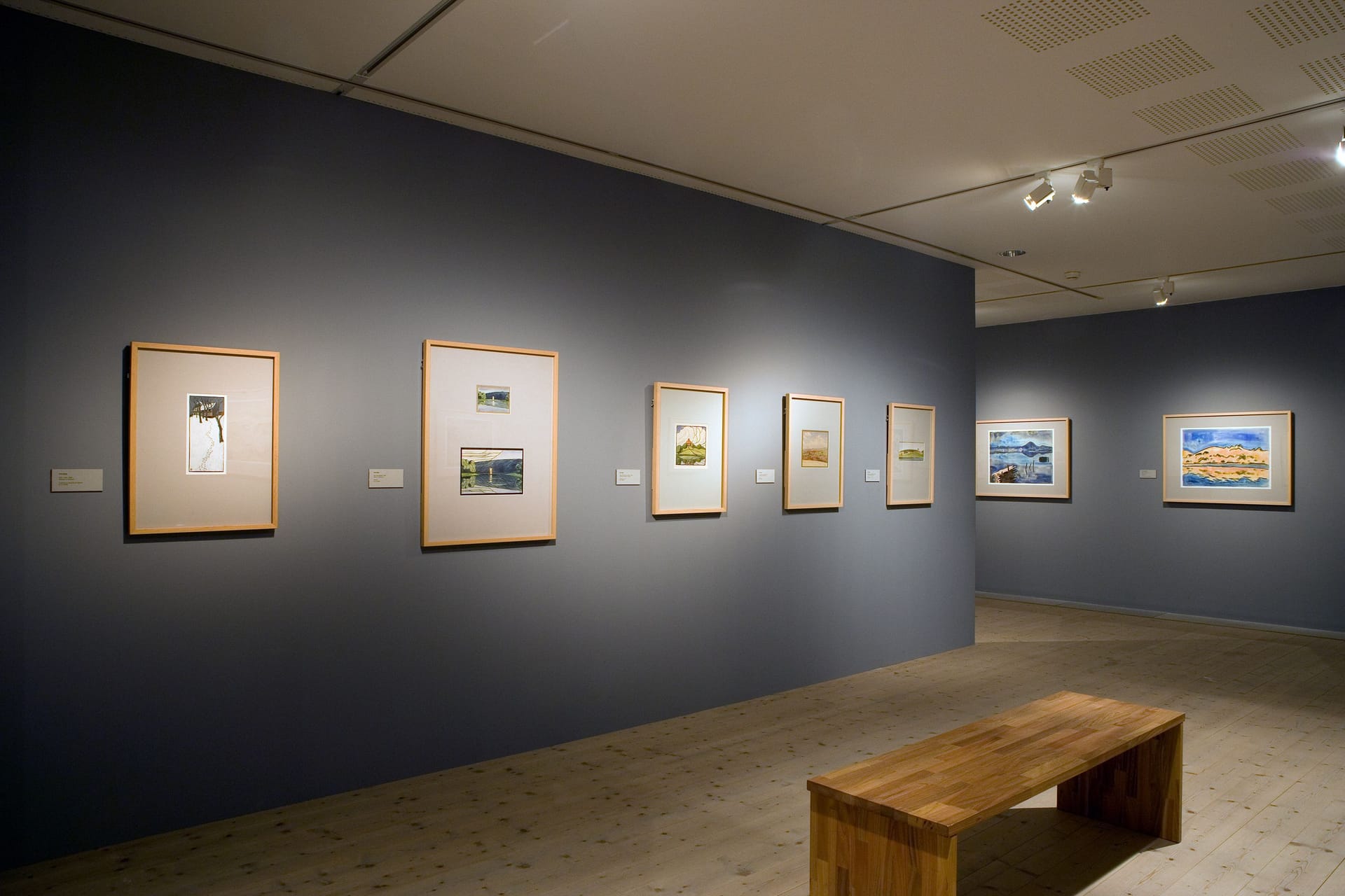 Gray exhibition room with paintings on the wall