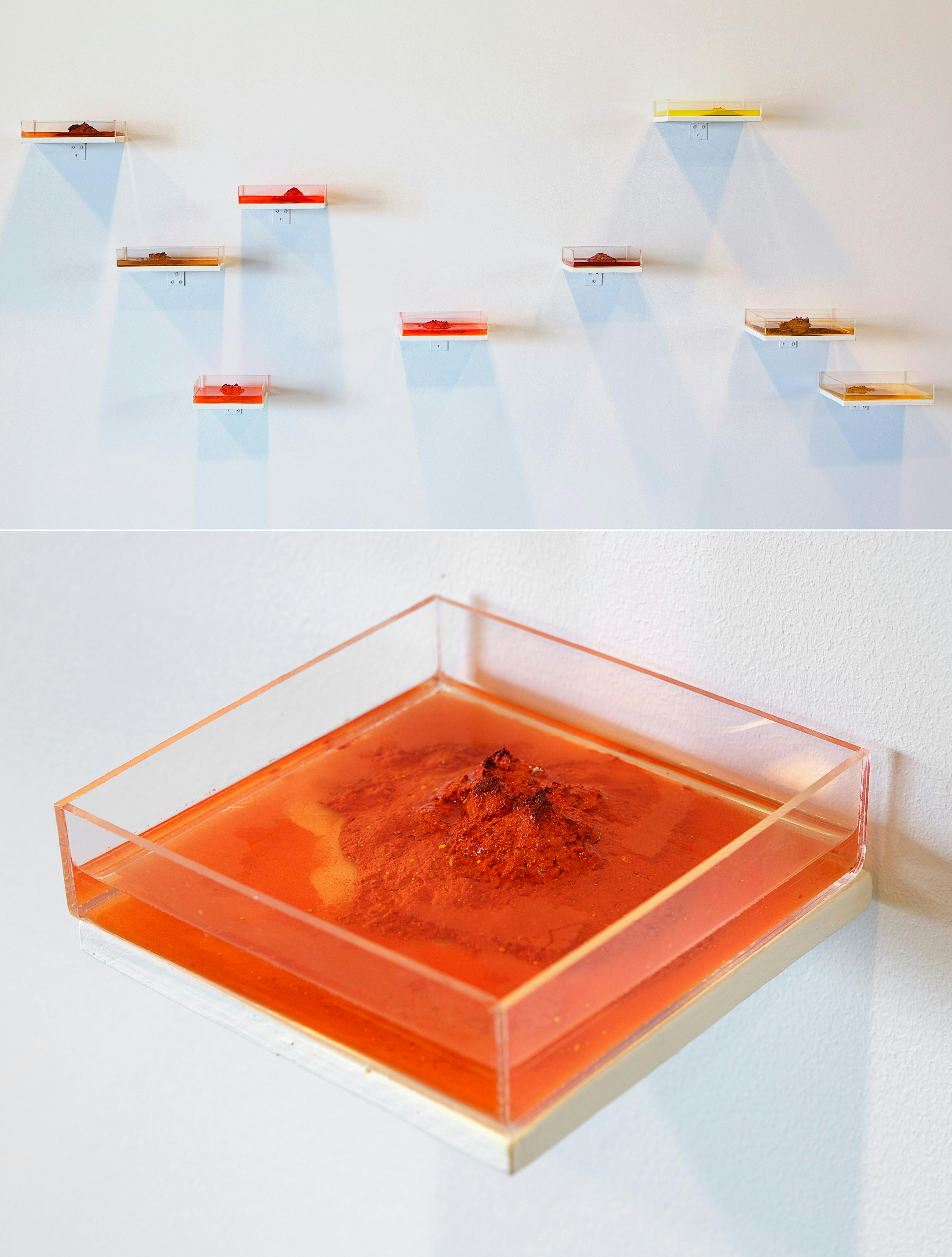 Gunilla Hanssons verk Pigmentöar, kvadratiska vattenbehållare med vatten och högar av pigment på väggen