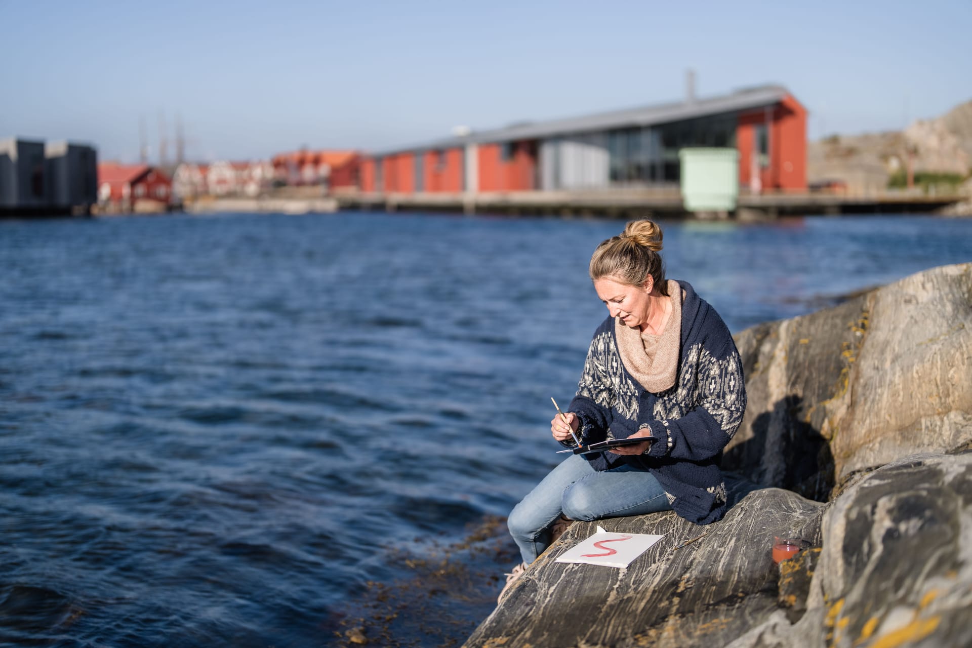Person paints on a rock with the museum in the background