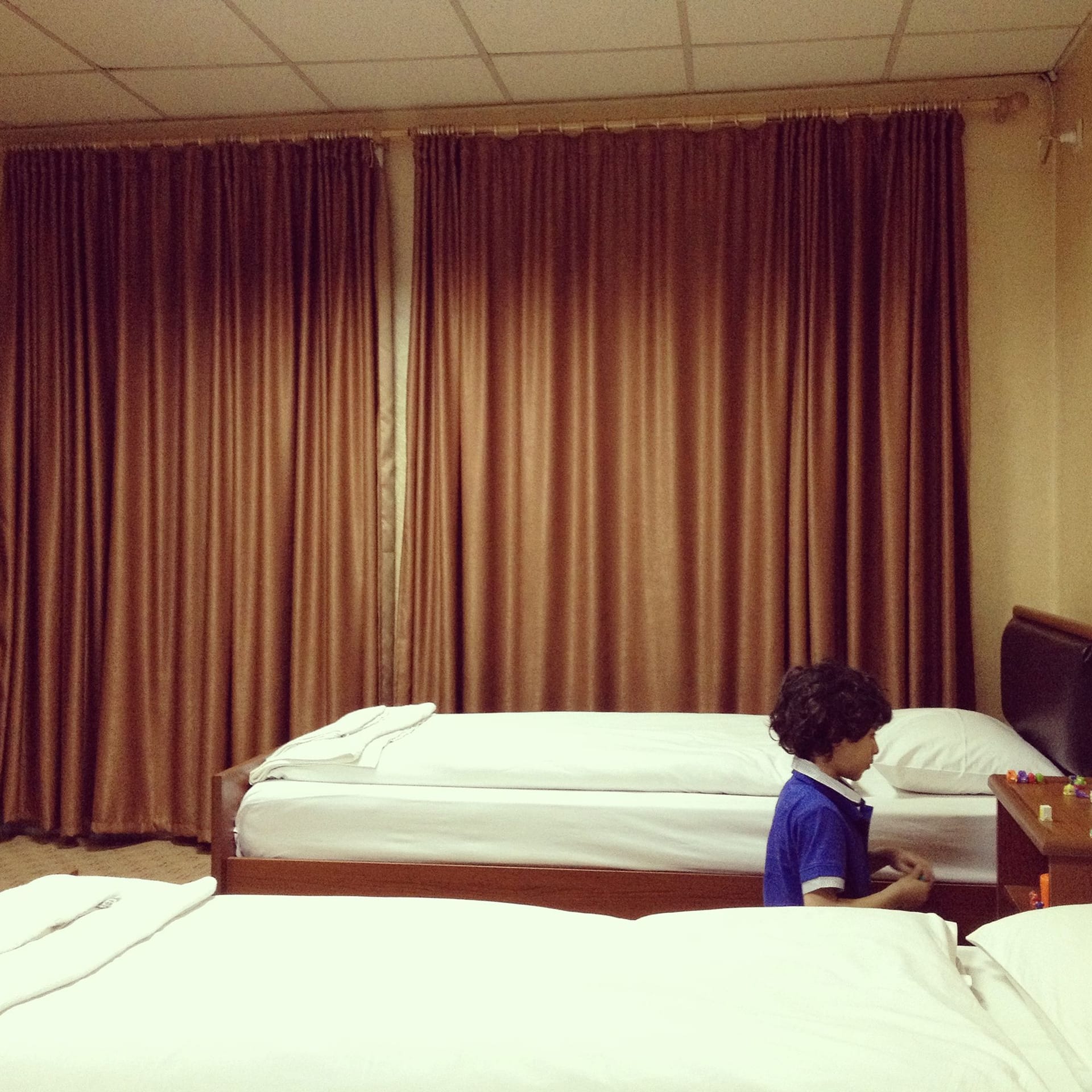 Image of room with two beds and a child on the floor