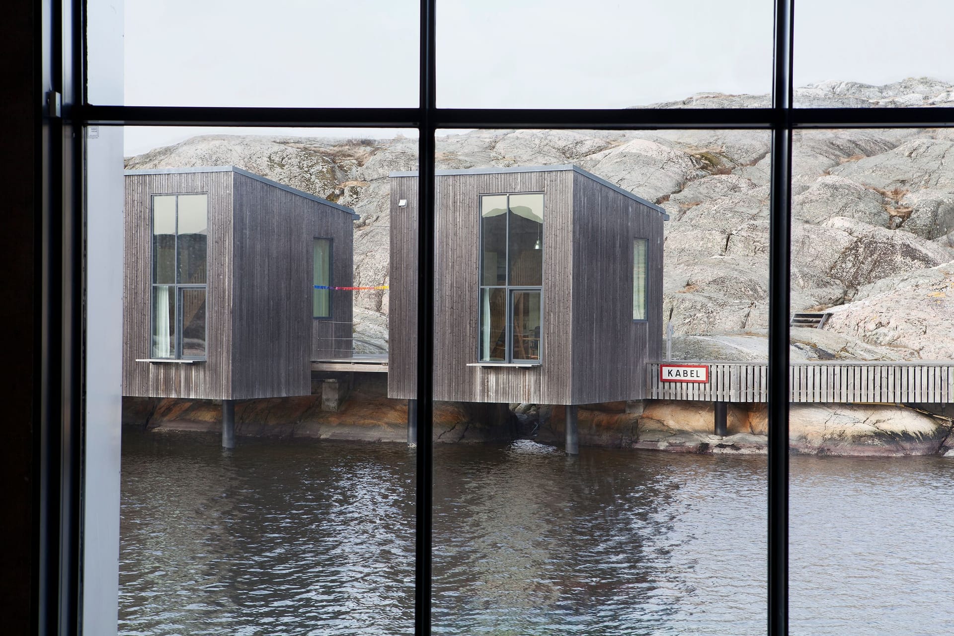 Guest studios outside The Nordic Watercolour Museum seen from a window, with a colorful artwork hanging between them