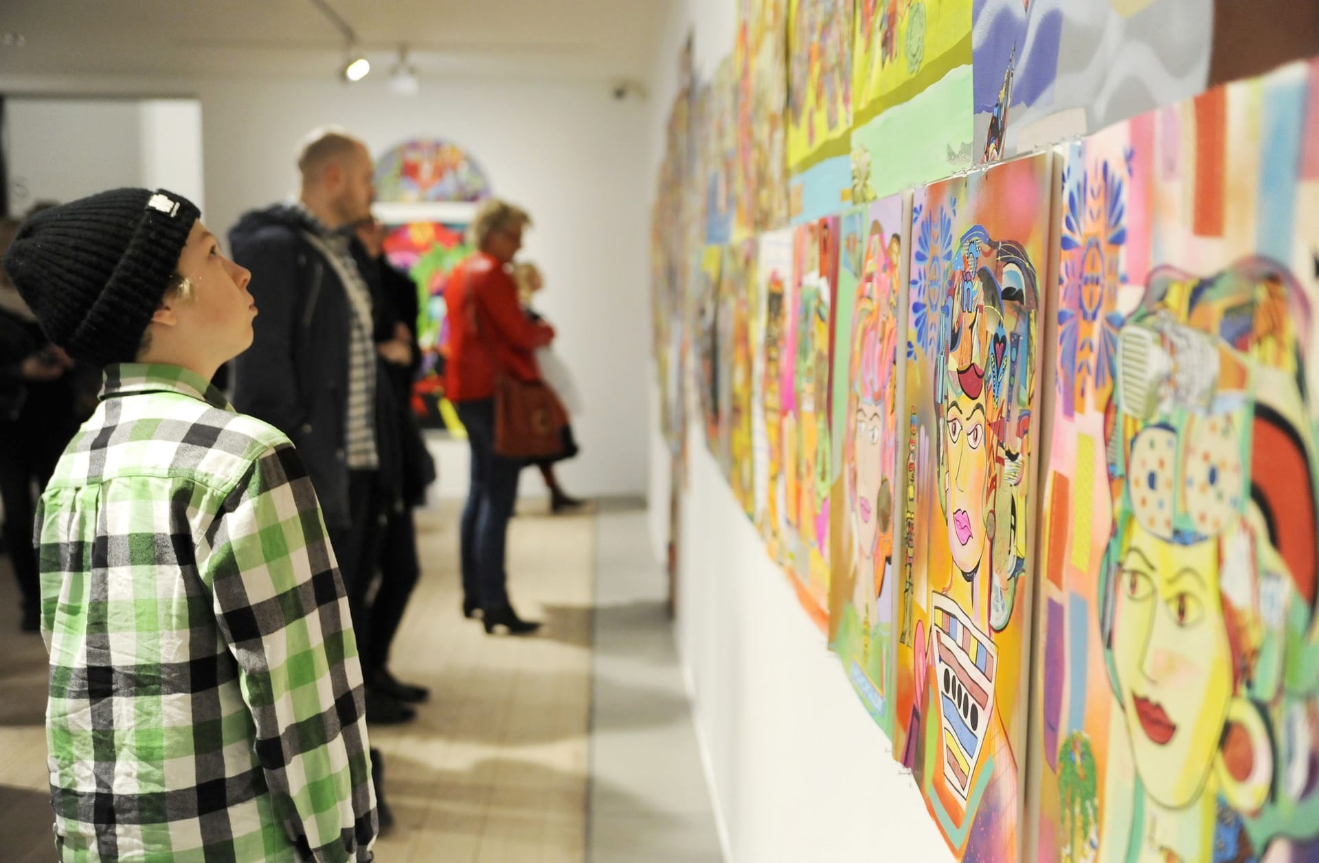 Young visitor with cap on left looking at painting on right