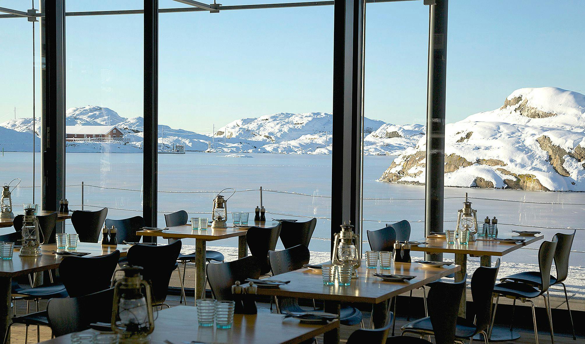 Utsikt från restaurang Vatten över snötäckta klippor och is på havet