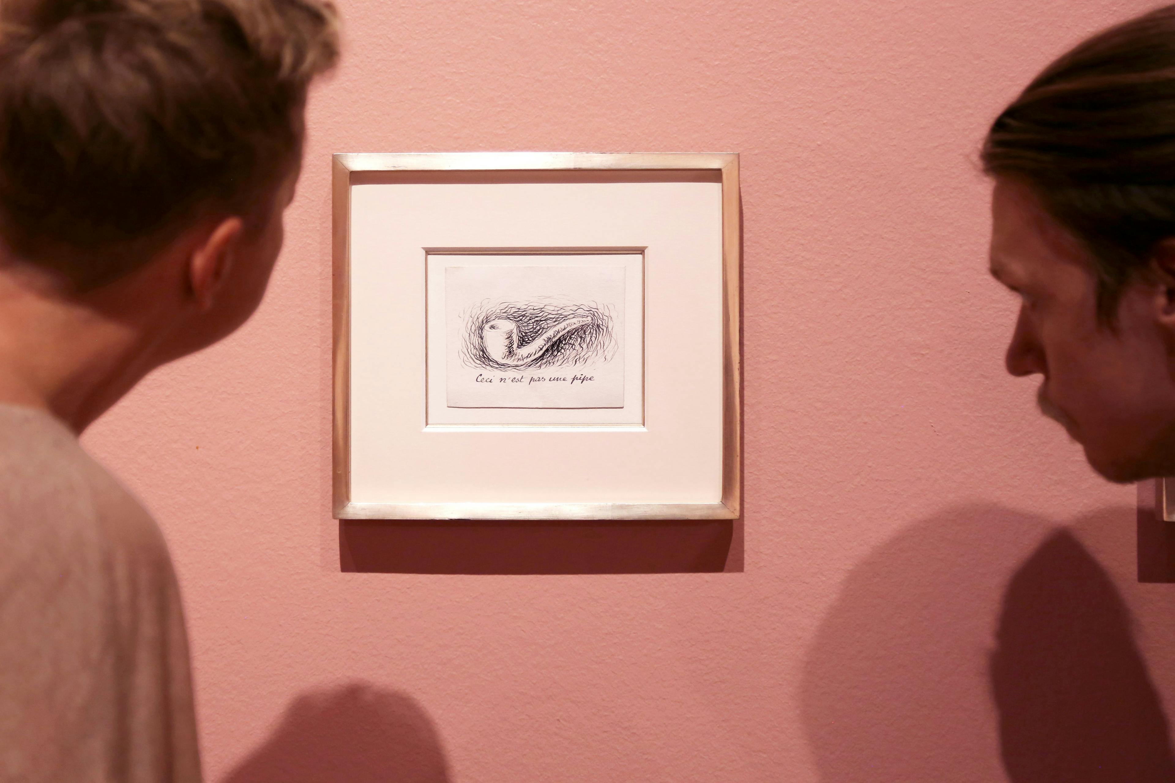 Siluett av två besökares huvuden som tittar på ett konstverk av René Magritte