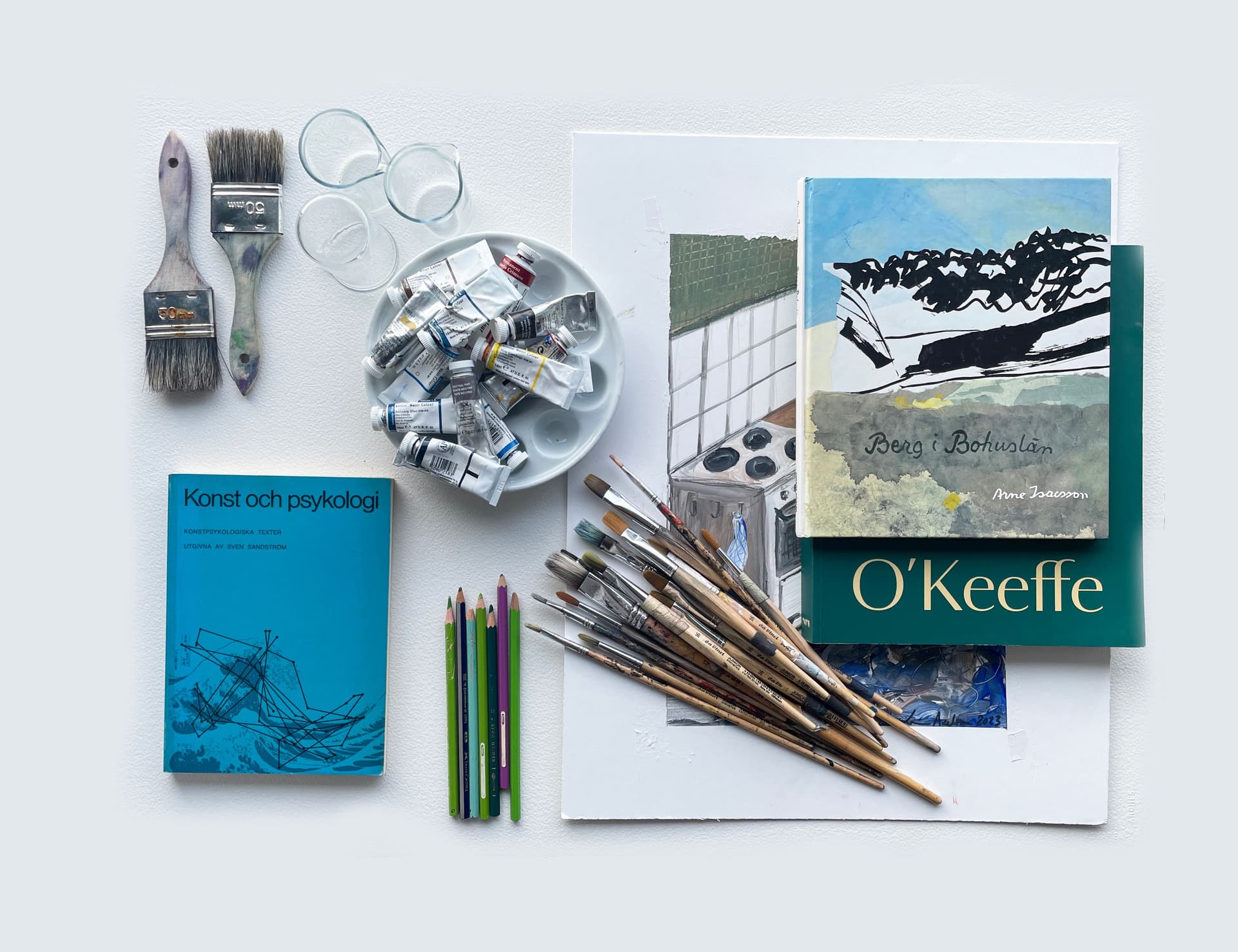 Ett stilleben med penslar, block, färgtuber och andra konstnärsmaterial