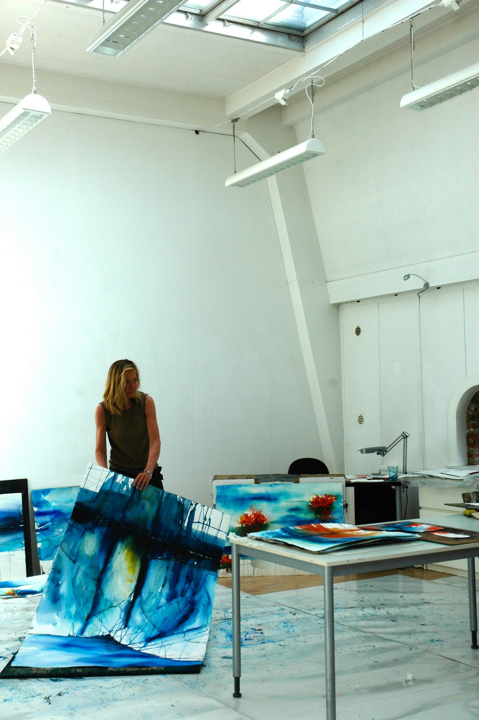 Ulla Ohlson in the studio, holding the painting Sea Blues