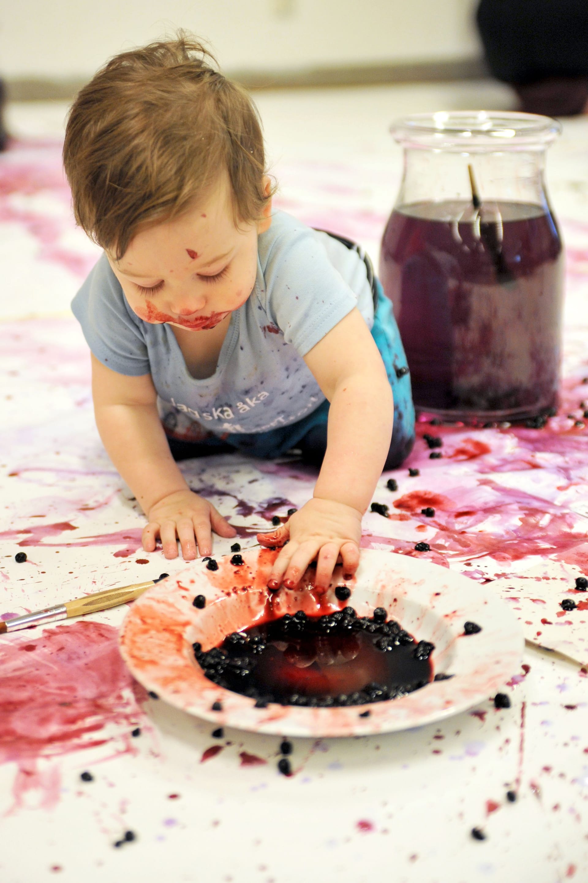 Baby messing with blueberries on the floor