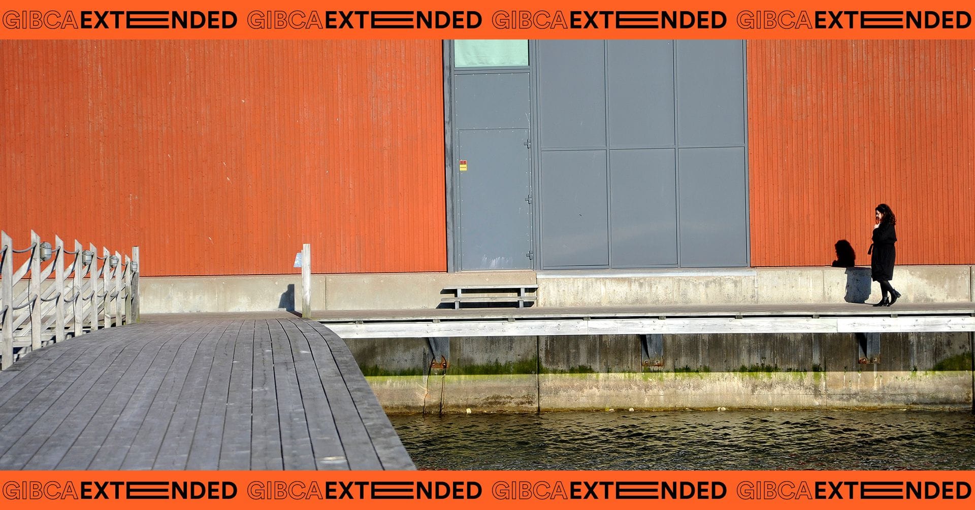Picture of the museum's red facade and person walking to the right in picture